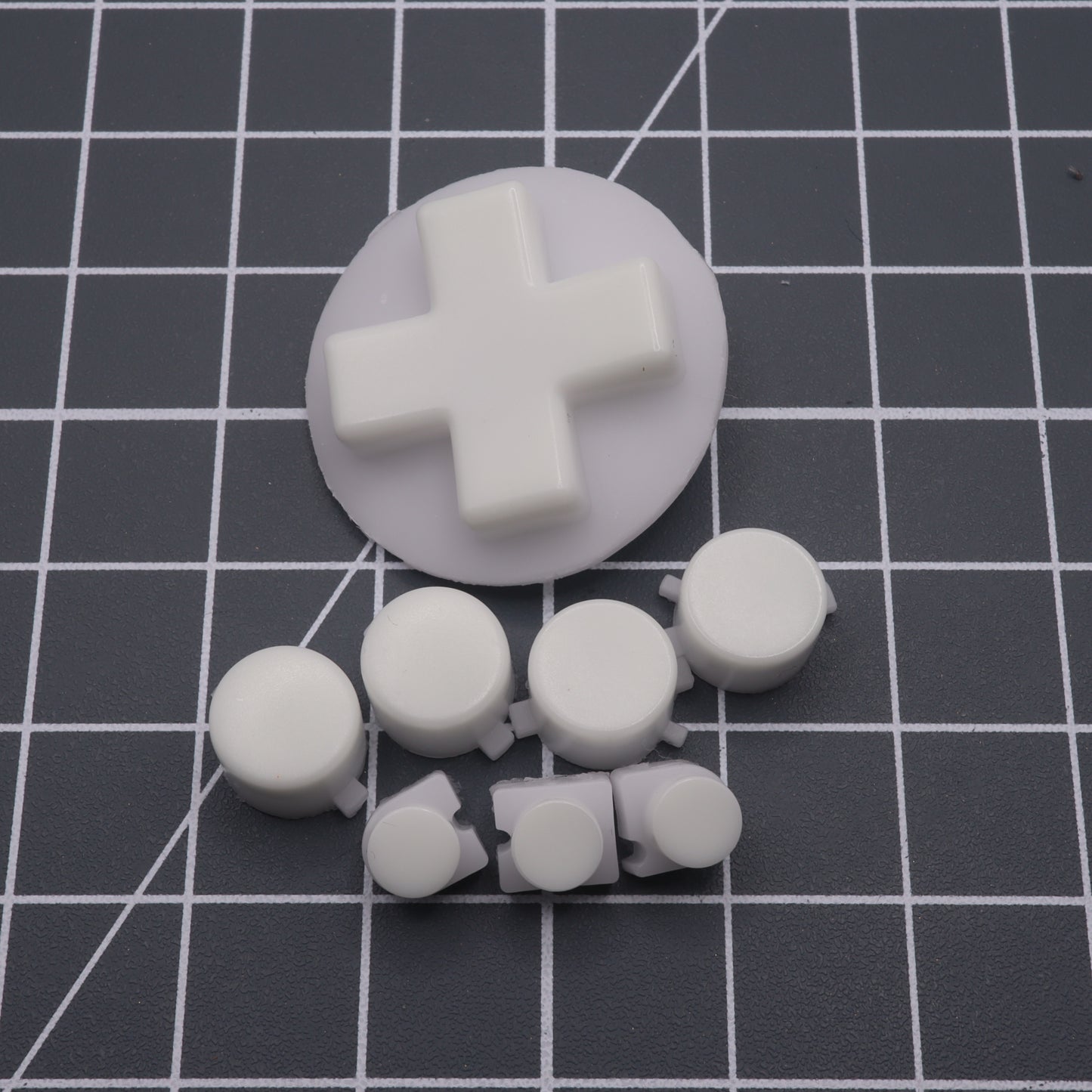 GITD Green custom button set for Analogue Pocket features white plastic buttons, a cross-shaped directional pad, and round buttons in a grid pattern, crafted with handmade molds for superior precision and quality.