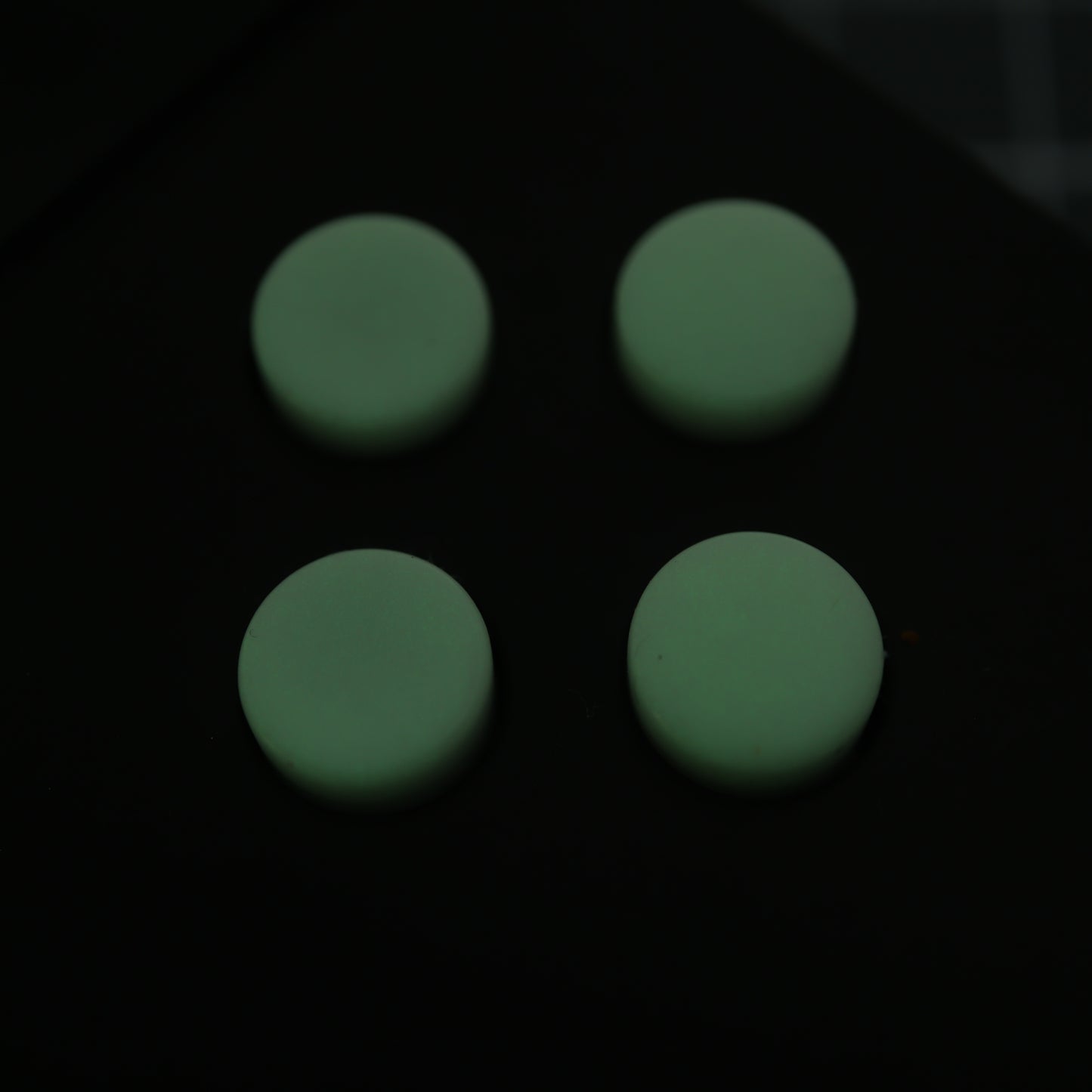 The Analogue Pocket features four custom GITD Green buttons, crafted using handmade molds and arranged in a two-by-two grid on a dark surface.