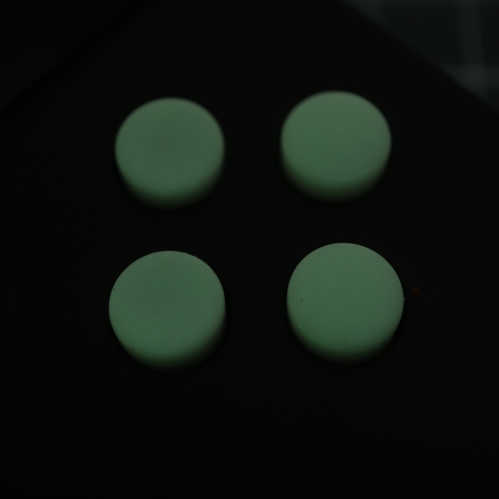 The Analogue Pocket features four custom GITD Green buttons, crafted using handmade molds and arranged in a two-by-two grid on a dark surface.