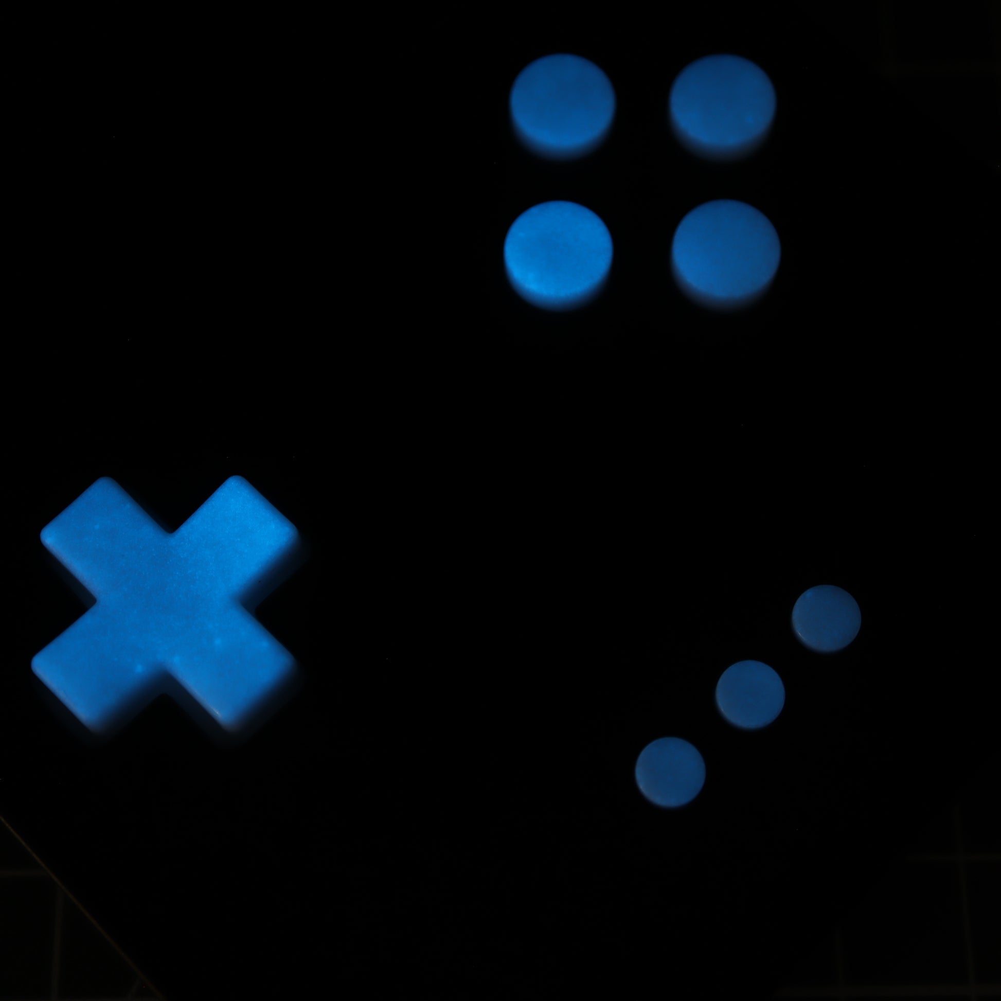The Analogue Pocket - Custom Button - GITD Blue features glowing blue gaming controller buttons on a black background, including a directional pad and four custom-cast buttons made from handmade molds.
