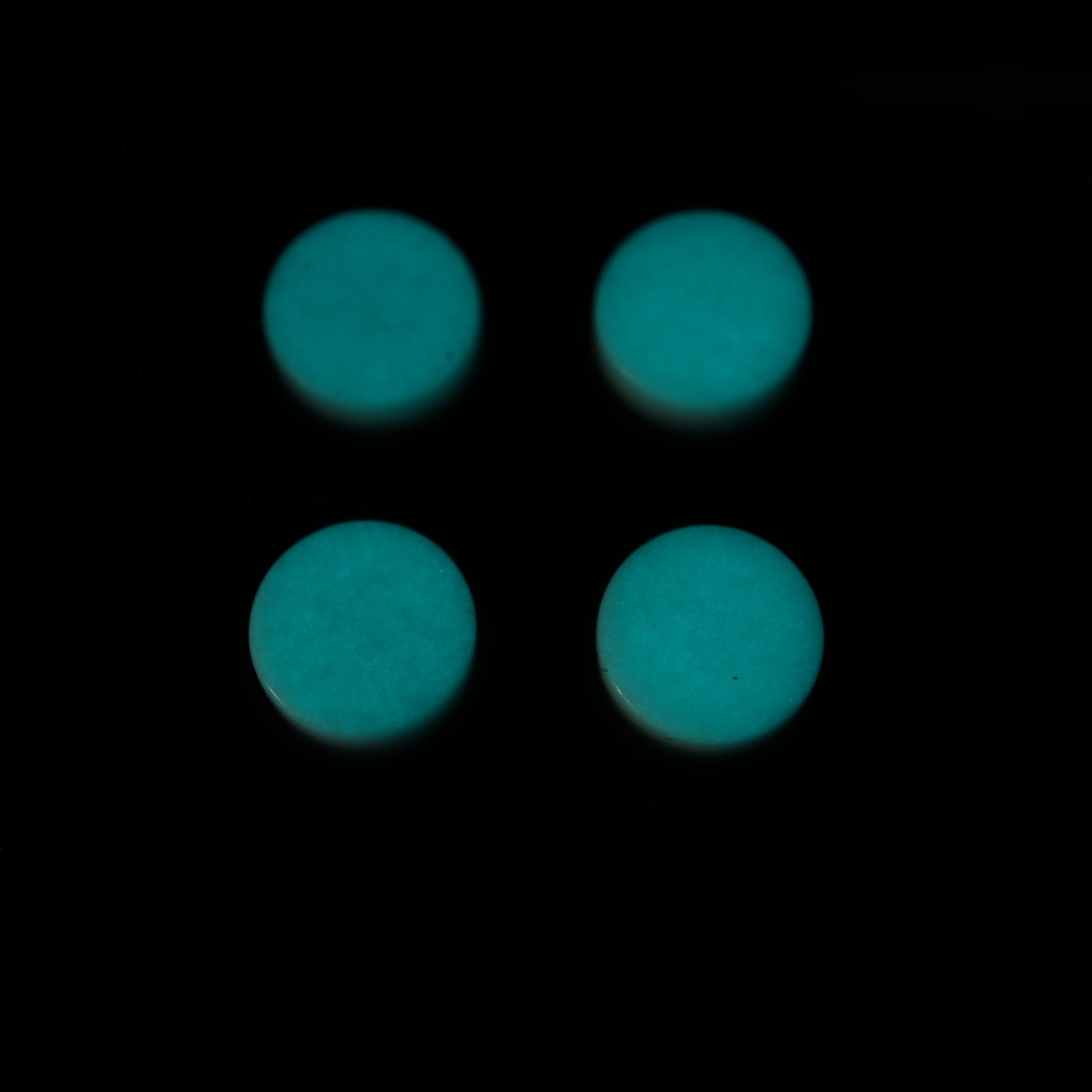 Four GITD Aqua custom-cast buttons for the Analogue Pocket are arranged in a square on a black background.