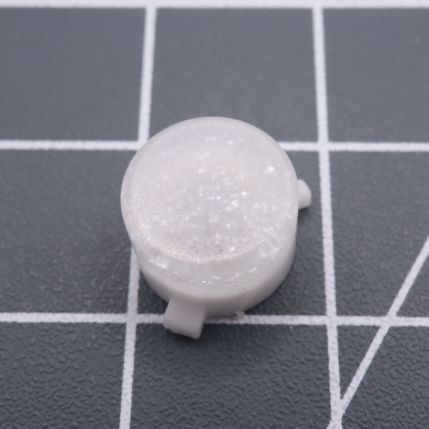 Pearl white custom button for Analogue Pocket, translucent and round plastic, shown on a gray grid background.
