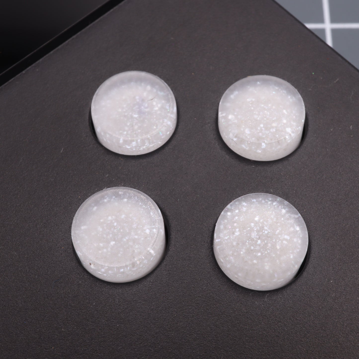 The Pearl White Analogue Pocket custom buttons are four translucent, round silicone grips with a glittery texture on a dark surface, crafted from handmade molds.