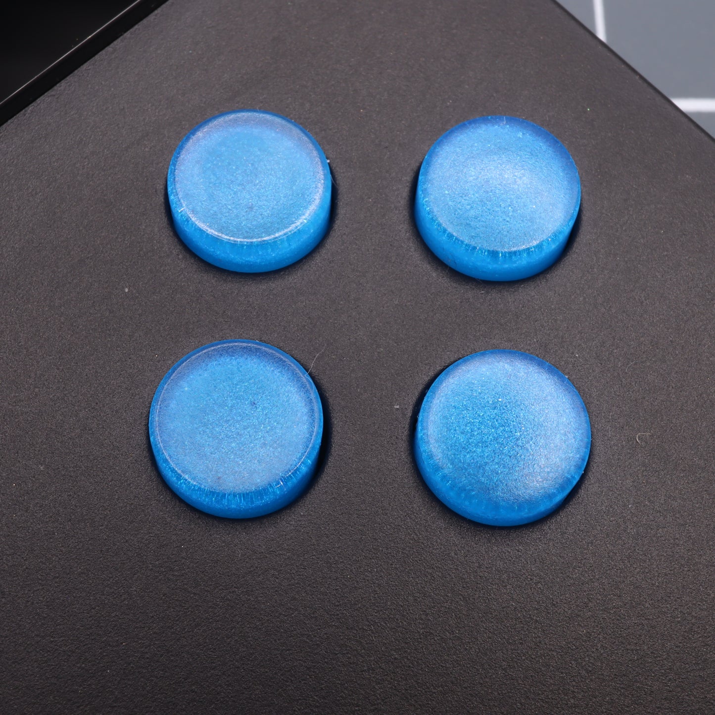 Four Analogue Pocket - Custom Button in Blueberry Candy rest on a black surface, crafted with precision from handmade molds.
