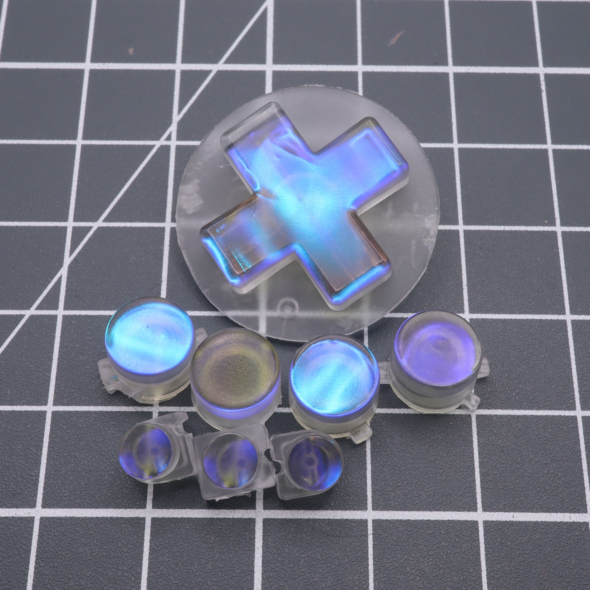 The Analogue Pocket - Custom Button - Midnight Opal, with its transparent blue design crafted from handmade molds, rests gracefully on a grid surface, blending form and function for an unmatched gaming experience.