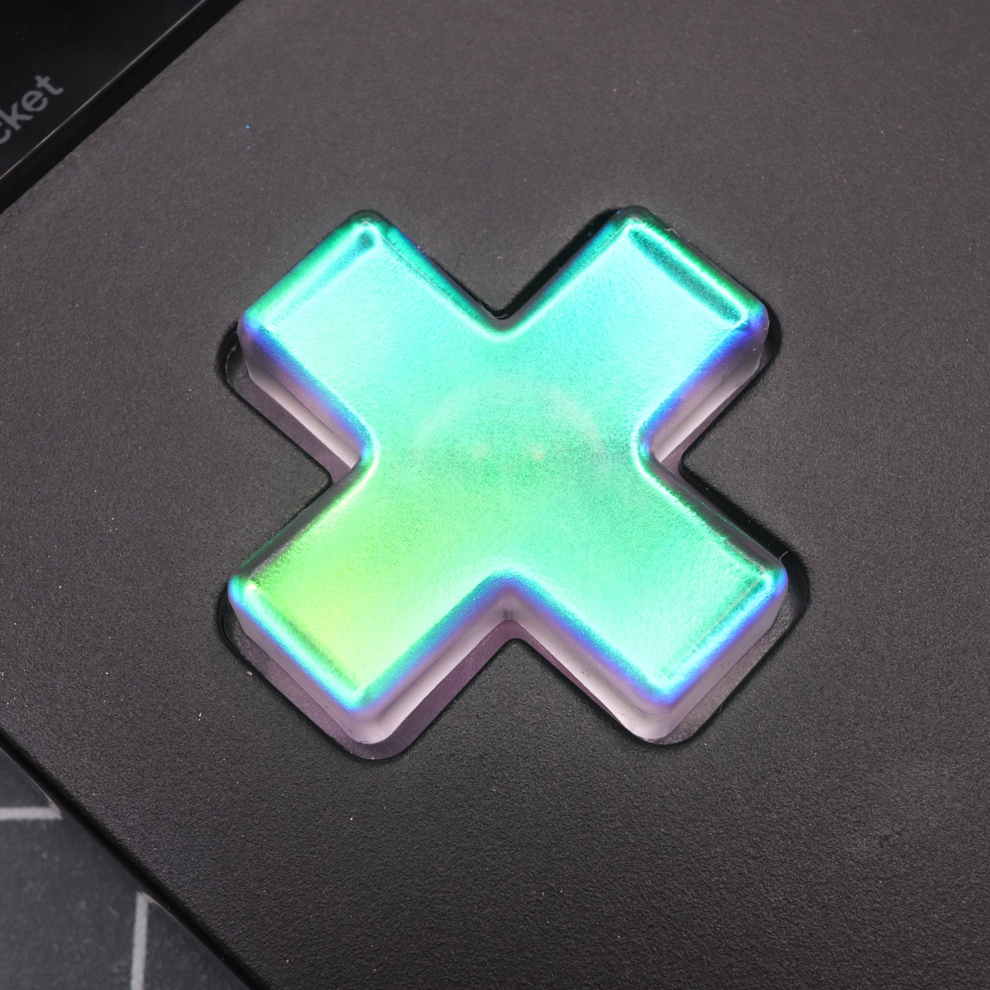 A luminous close-up of the Analogue Pocket - Custom Button in Cool Opal shimmers with a glowing rainbow effect on a dark surface, ideal for Retro Modding enthusiasts.