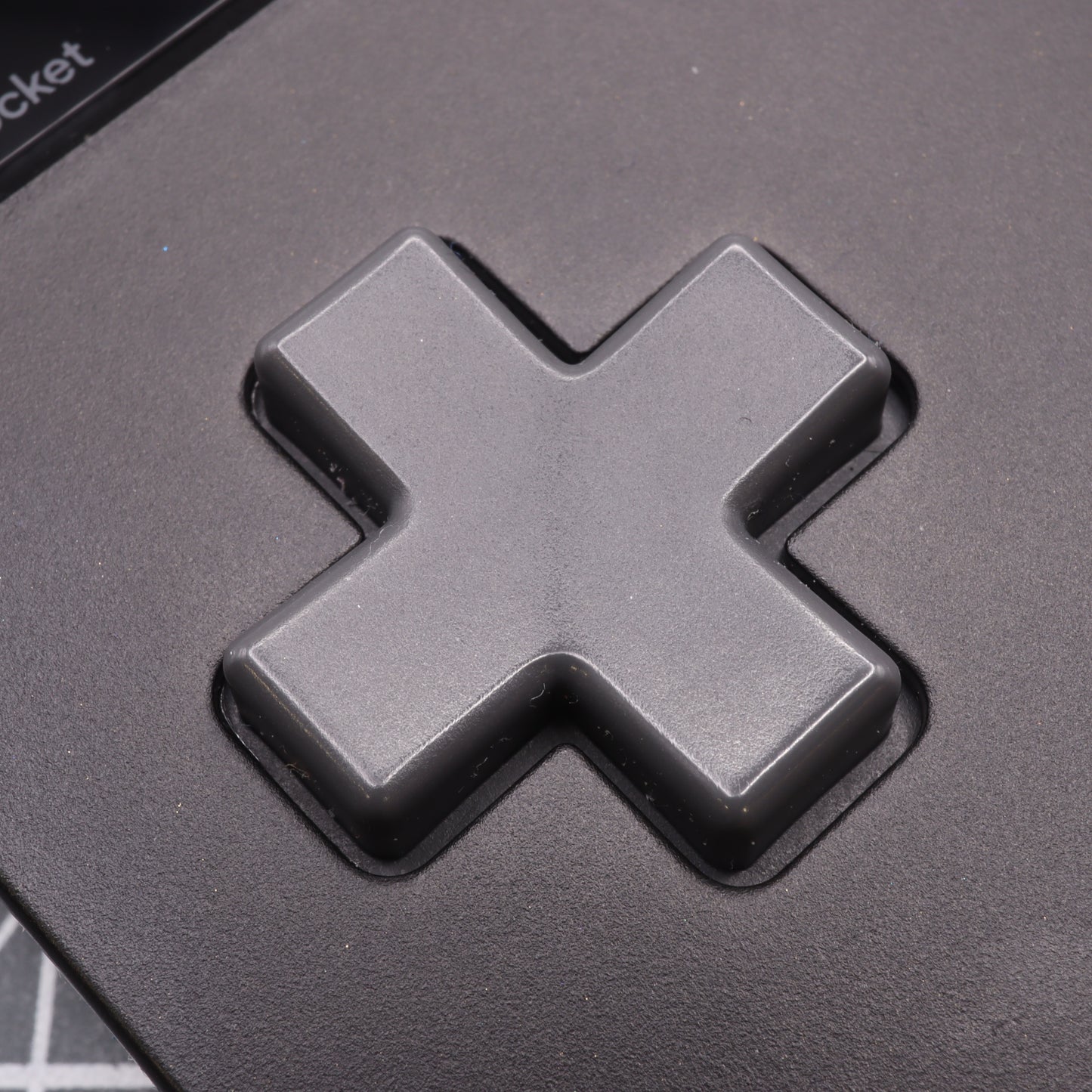 Close-up of the Analogue Pocket - Custom Button in a black cross shape, designed like a Game Boy DMG button with precision-crafted, handmade mold techniques.