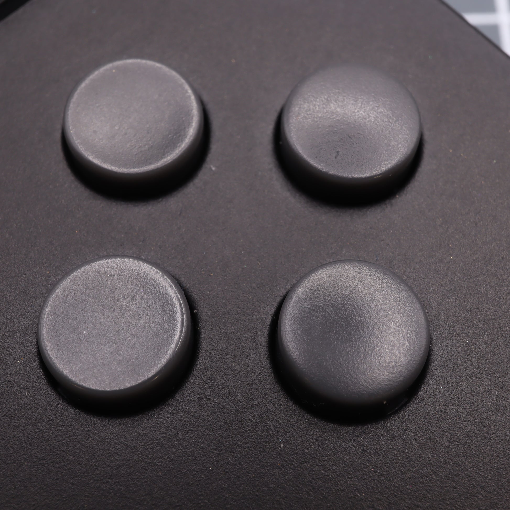 A close-up of the Analogue Pocket's custom DMG Play it Loud Style buttons showcases four circular, custom-cast buttons arranged in a square on the sleek black surface.
