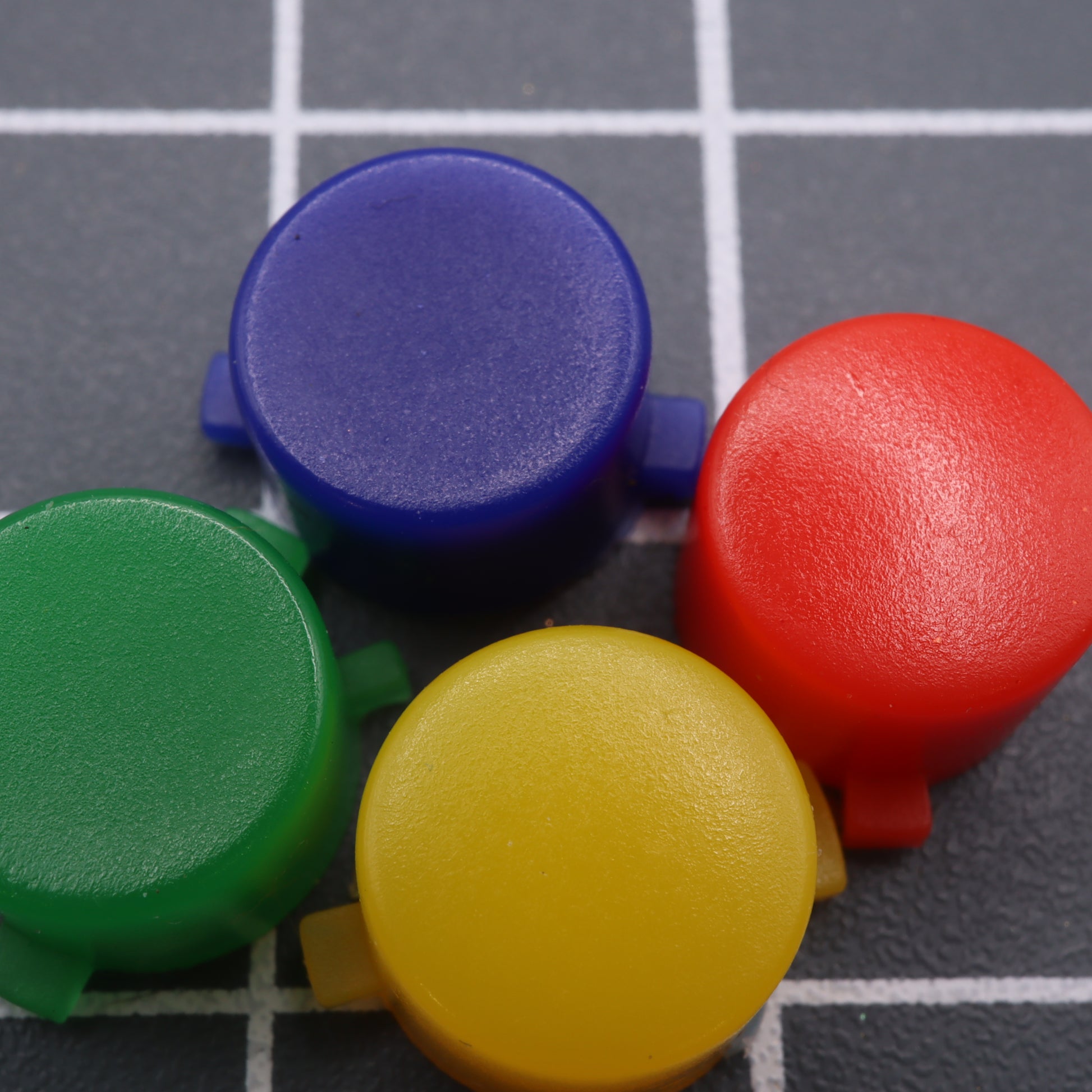 The Analogue Pocket - Custom Button - SNES Style includes four buttons in blue, red, yellow, and green arranged in a cluster on a grid surface.