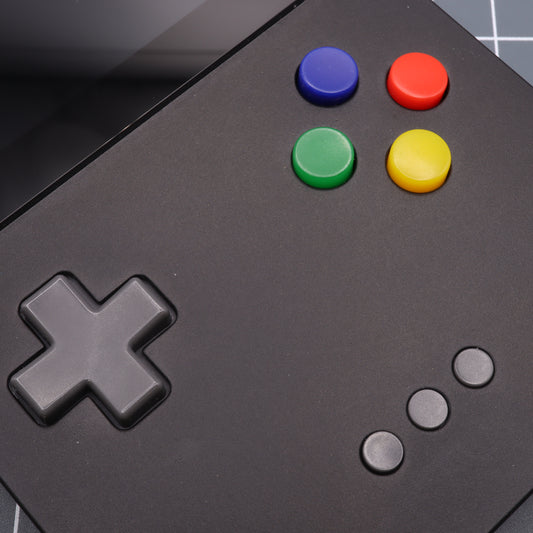Close-up of the Analogue Pocket - Custom Button - SNES Style, a black gaming controller with custom-cast buttons and a directional pad, featuring vibrant blue, red, green, and yellow accents.