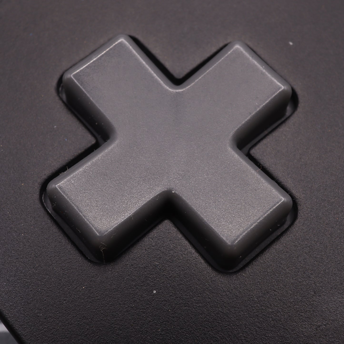 Close-up of a black cross-shaped directional pad on the Analogue Pocket controller, featuring SNES style custom-cast buttons for a unique tactile experience.