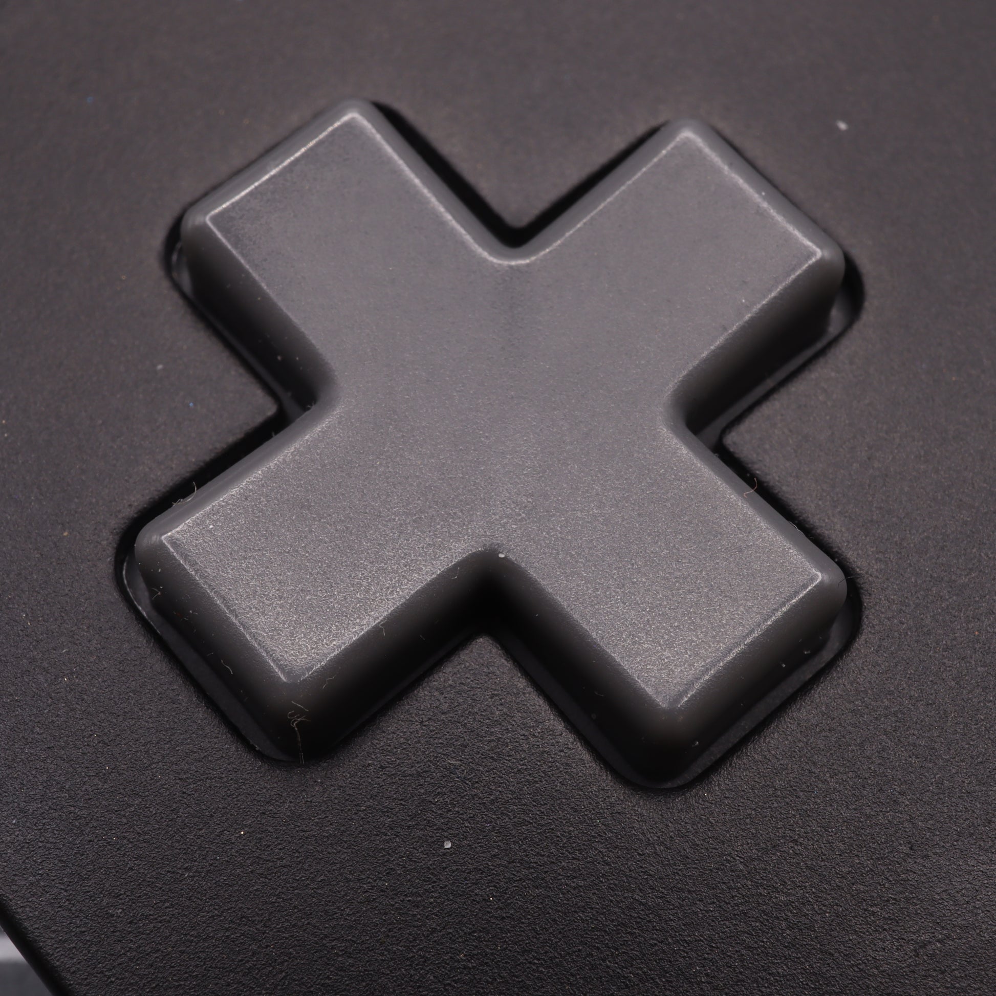 Close-up of a black cross-shaped directional pad on the Analogue Pocket controller, featuring SNES style custom-cast buttons for a unique tactile experience.