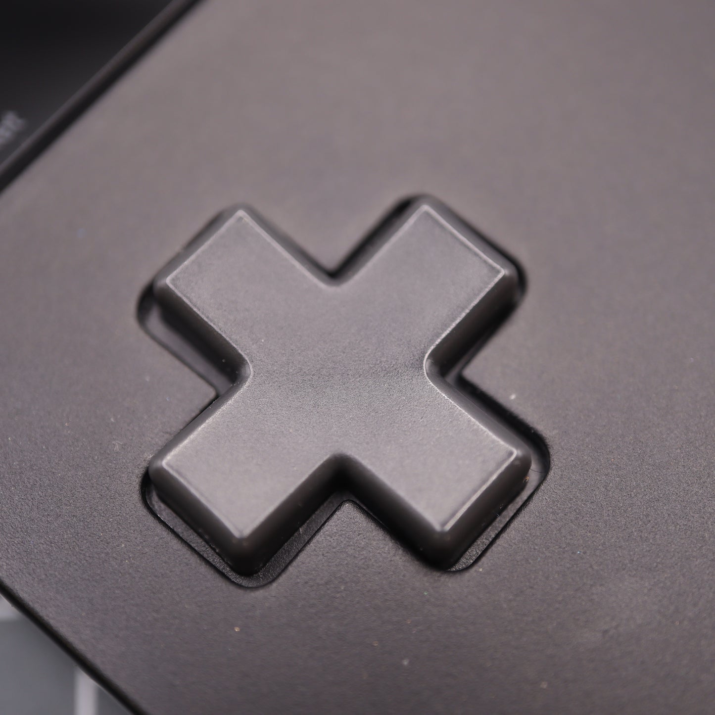 Close-up of a black cross-shaped button on an electronic device, reminiscent of the Analogue Pocket - Custom Button - Famicon Style.