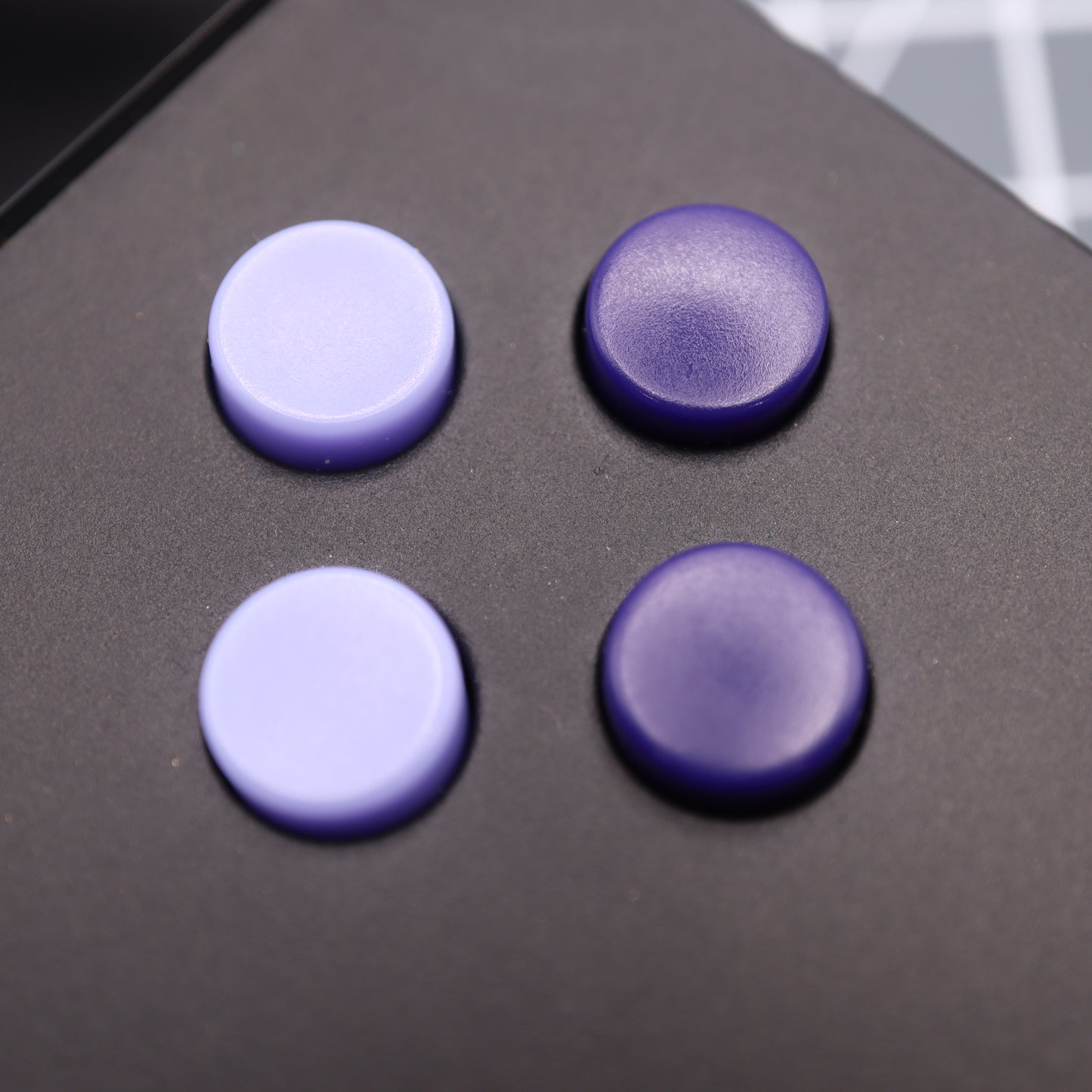 Four custom-cast, round purple buttons in a square formation adorn the sleek black surface of the Analogue Pocket - Custom Button - Famicon Style.