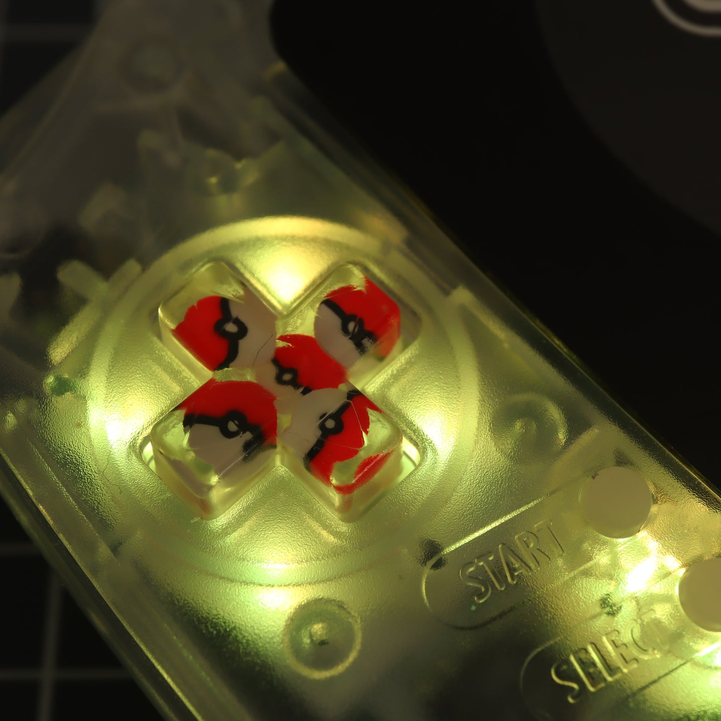 A close up of a labfifteen Game Boy Advance with custom-cast Pokeball buttons.