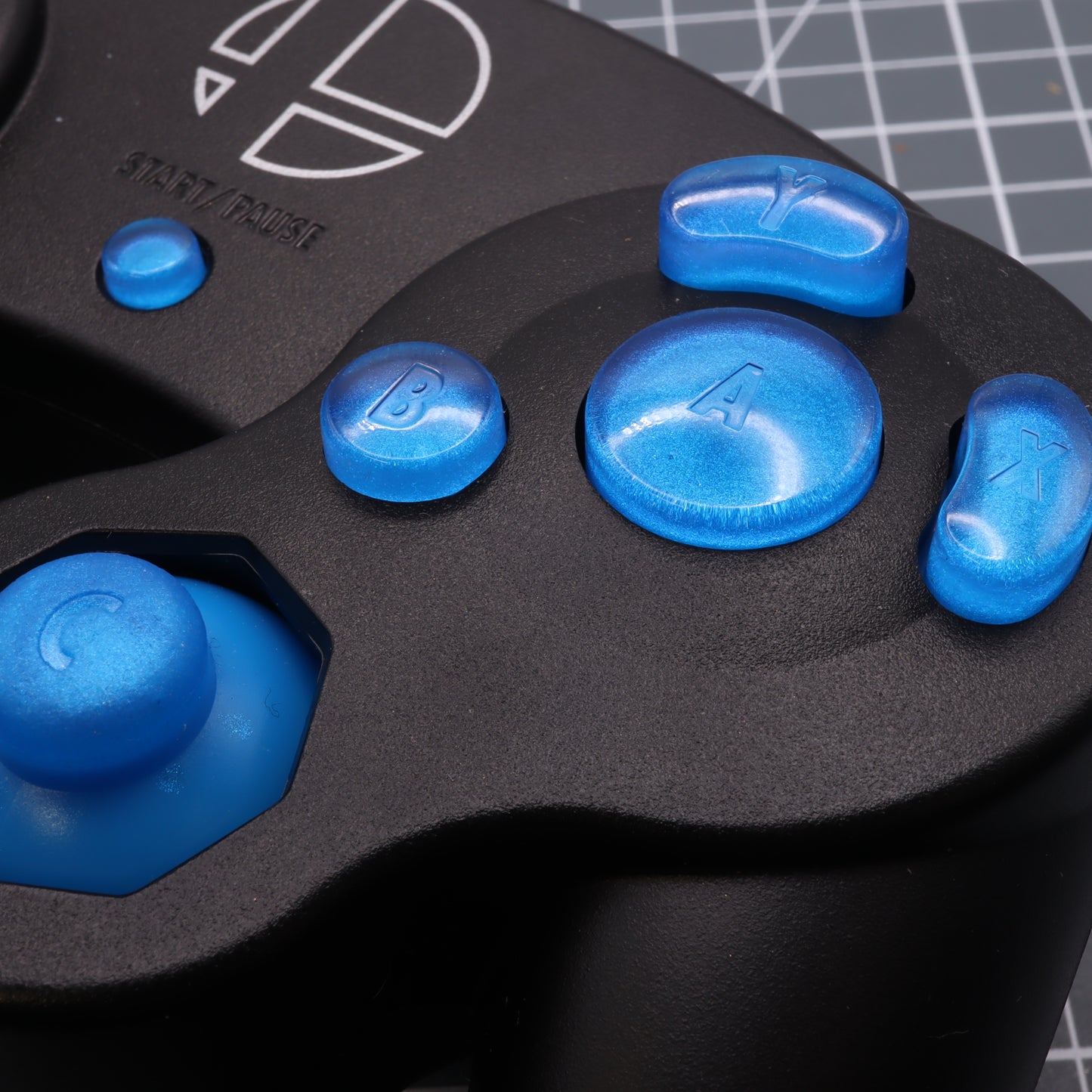 Close-up of a GameCube with custom-cast resin buttons showing letters x, a, b, y.