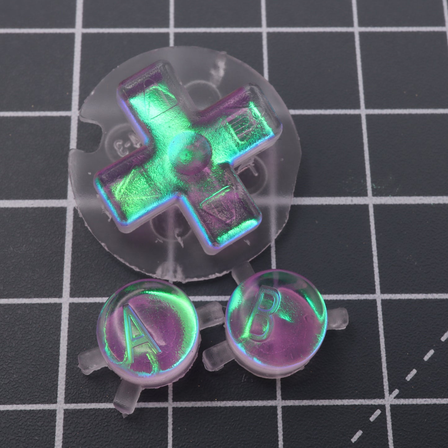 A set of Game Boy Color controllers with labfifteen Cool Opal custom buttons on a table.