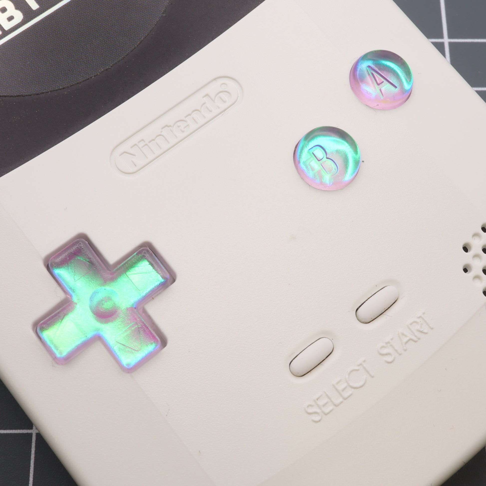 A white labfifteen Nintendo Game Boy Color with Cool Opal resin custom buttons.