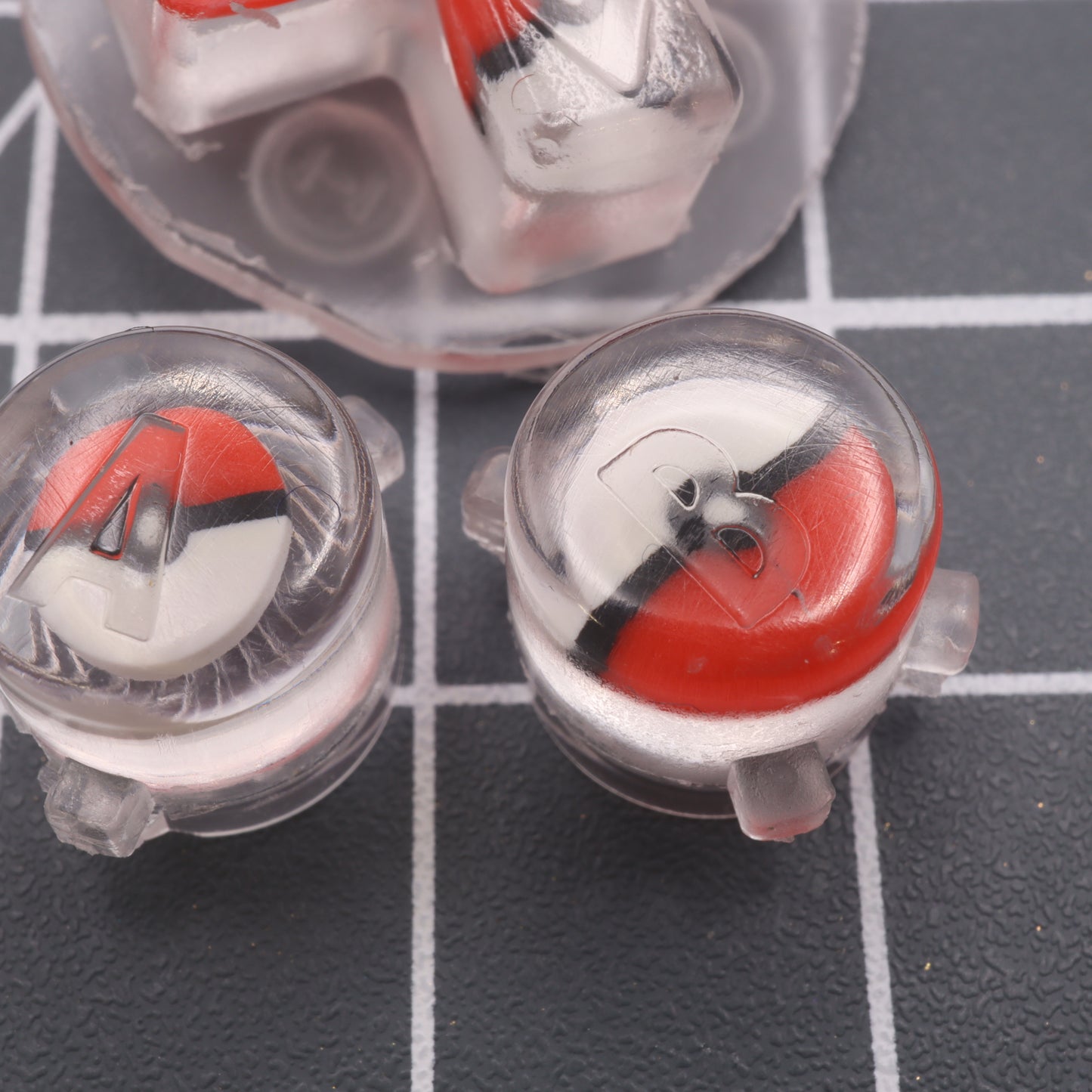 A group of labfifteen custom-cast Pokeball buttons on a Game Boy Advance d-pad grid.