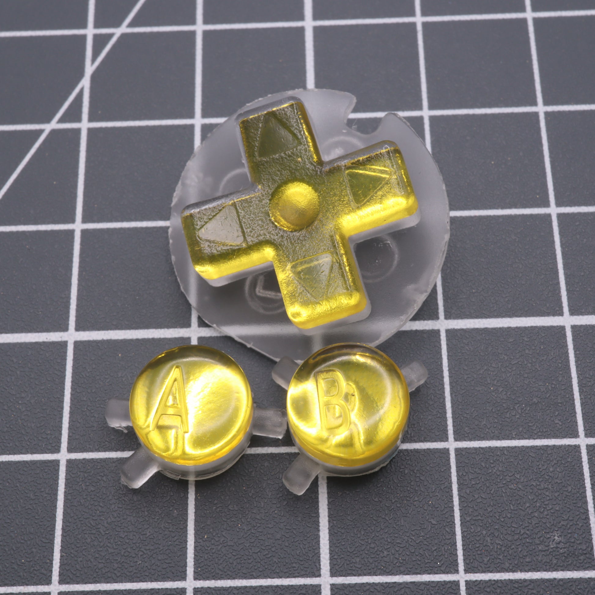 Game Boy Color buttons with lab fifteen co silver chrome gold yellow custom buttons on a table.