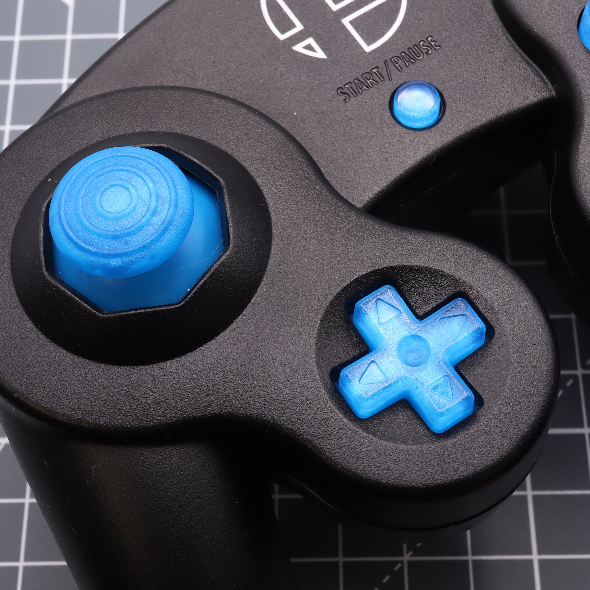 Close-up of a black GameCube controller with custom-cast blue buttons and directional pad.