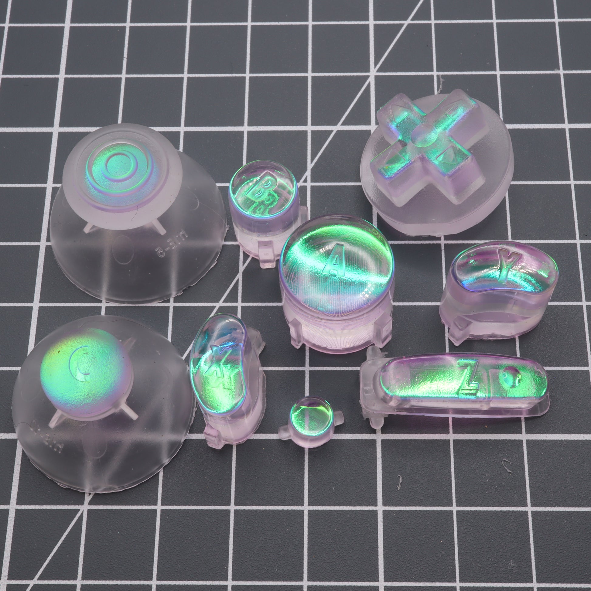 A collection of transparent, colorful mechanical keyboard keycaps with a GameCube - Custom Button - Cool Opal effect.