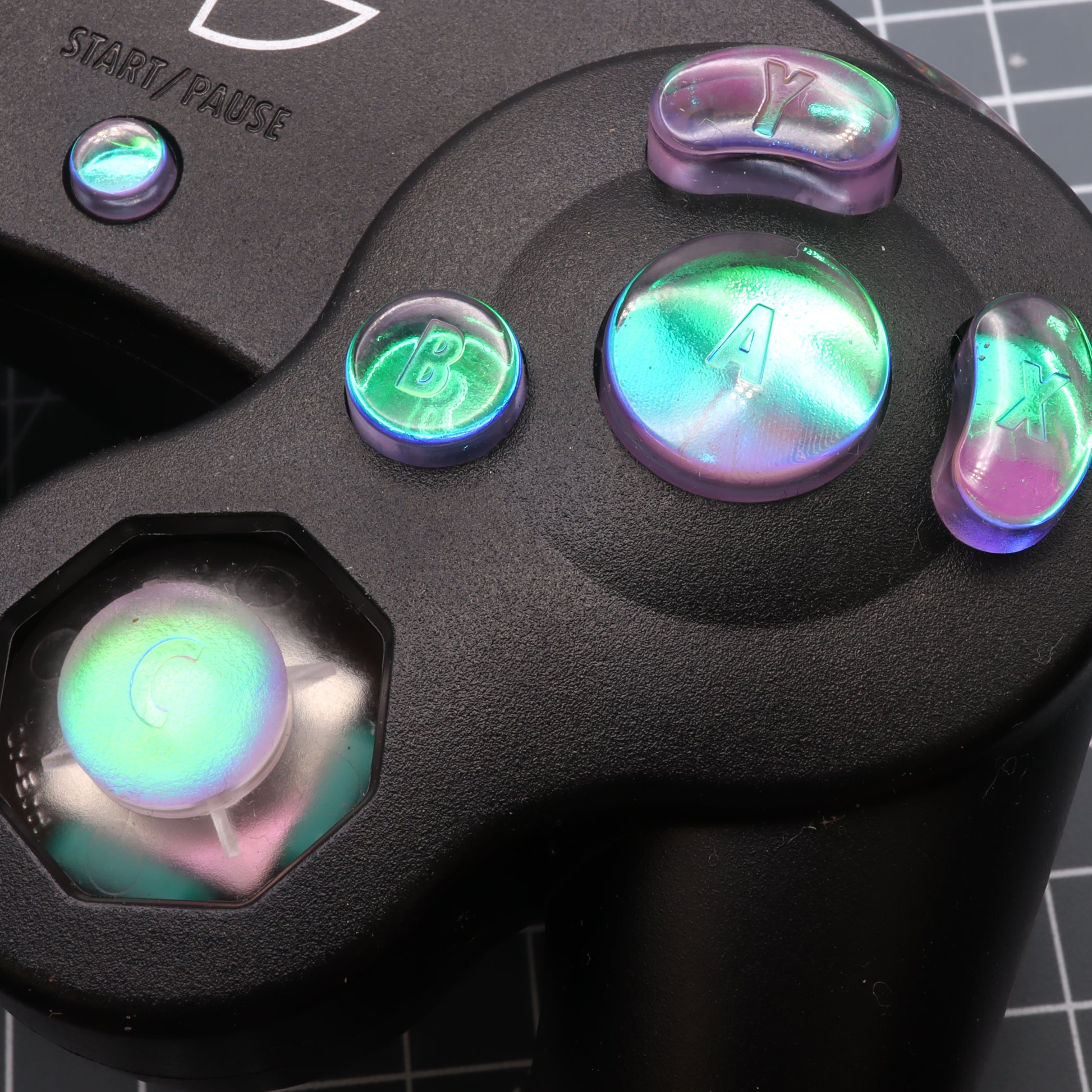 Close-up of a GameCube - Custom Button - Cool Opal controller's buttons a, b, c, and start/pause with Dichroic effect.