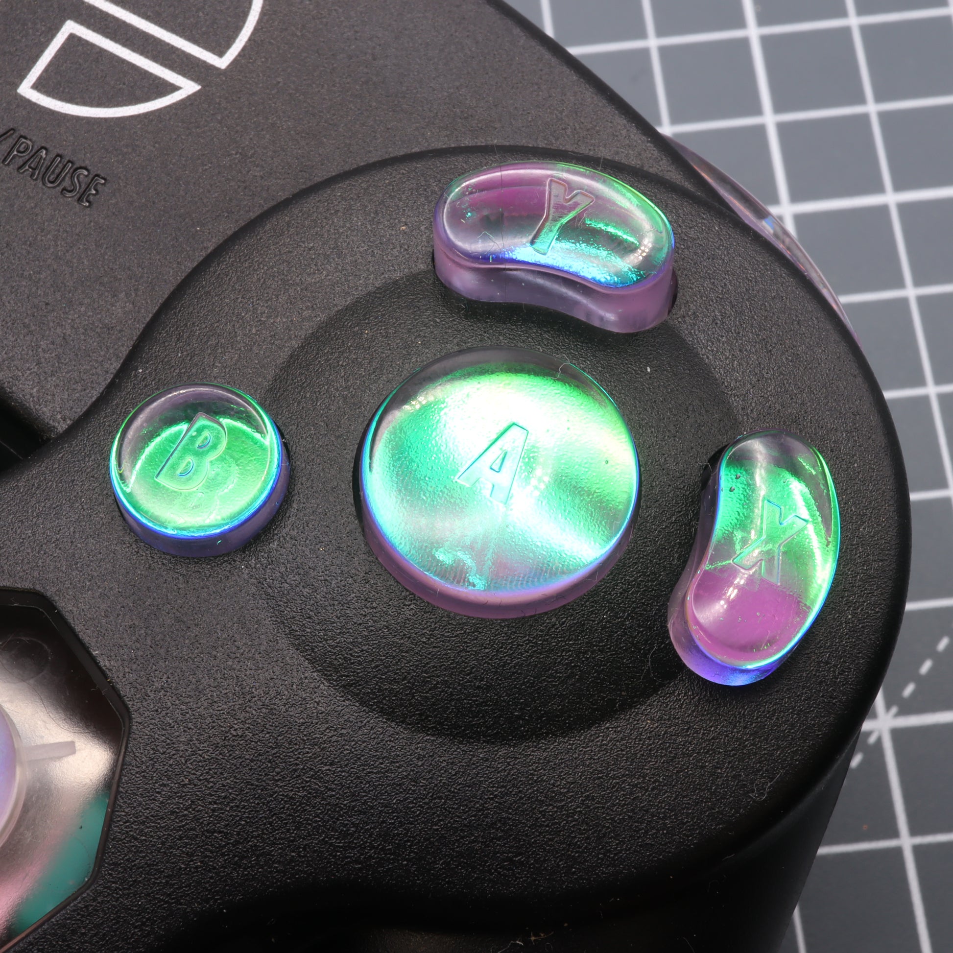 A close-up of a GameCube - Custom Button - Cool Opal controller's colorful abxy buttons with a reflective, dichroic effect.