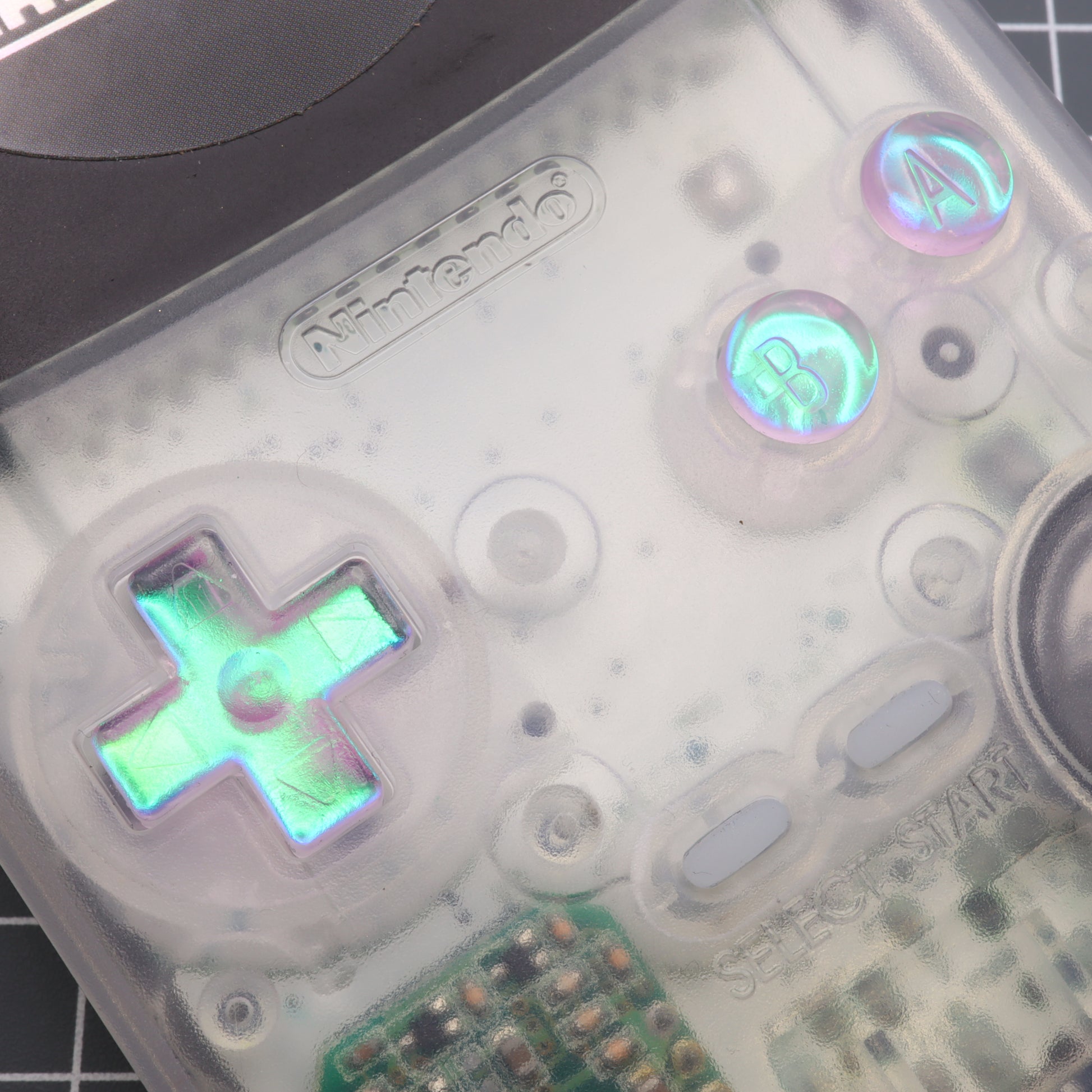 A labfifteen Game Boy Color - Custom Button - Cool Opal game controller is sitting on a table.