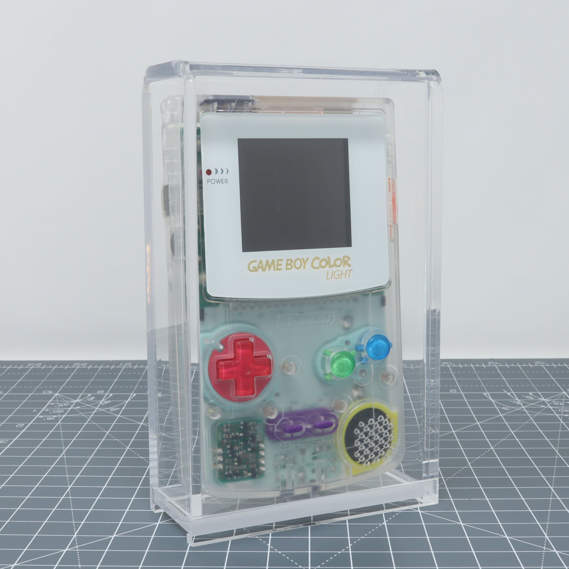 A transparent Game Boy Color displayed in a Game Boy Color - Display Capsule.
