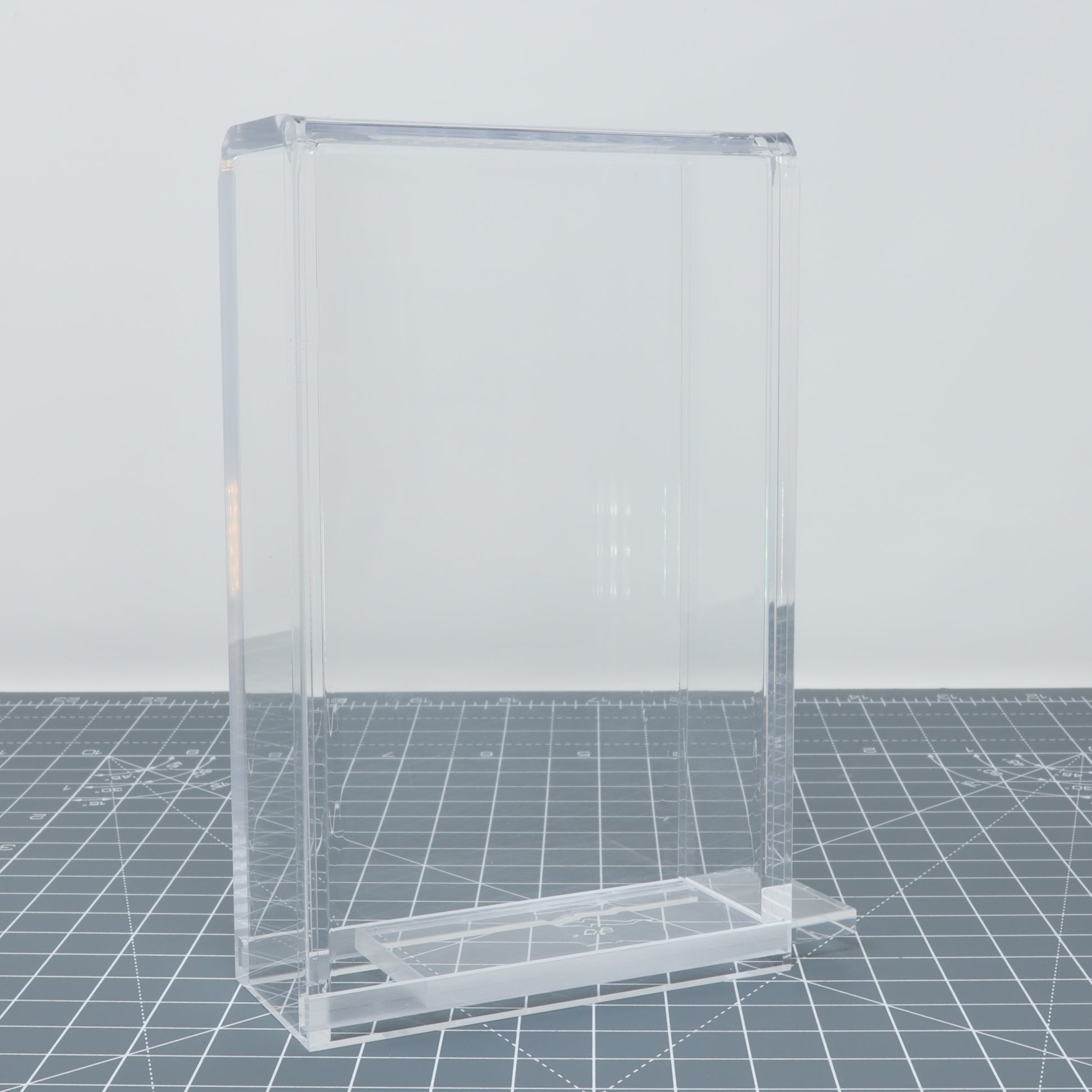 Transparent acrylic Game Boy Pocket display capsules on a gridded surface.